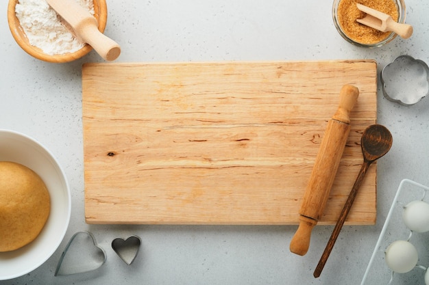 Baking ingredients and kitchen utensils on a white background top view Preparing heart sugar cookies Baking background Flour eggs sugar spices and a whisk on the kitchen table Flat lay