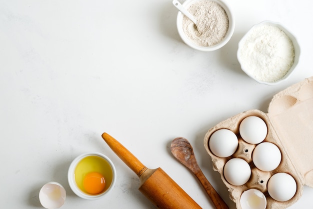 Baking ingredients for making homemade traditional bread or cakes on a light grey marble table.