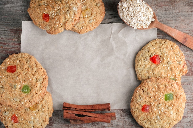 Cuocere, biscotti di avena in un flatlay con un cucchiaio di legno e bastoncini di cannella su carta da forno