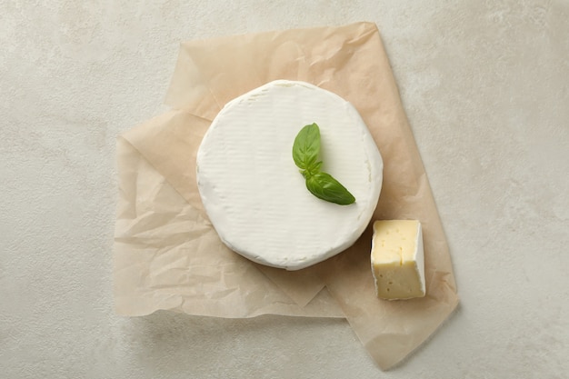 Baking paper with camembert cheese on white textured background