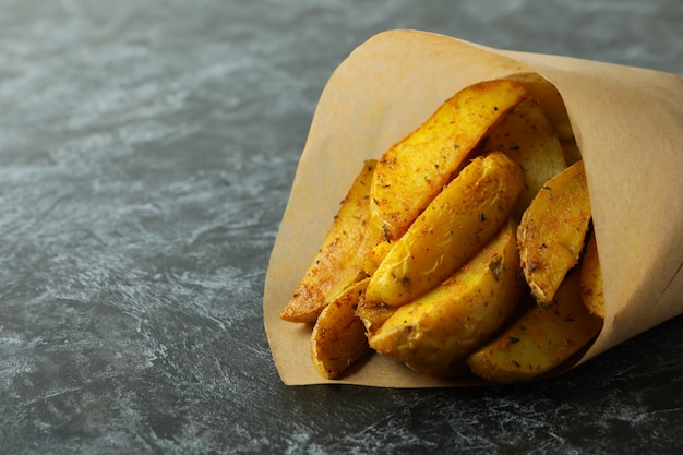 Baking paper with potato wedges on black smokey background