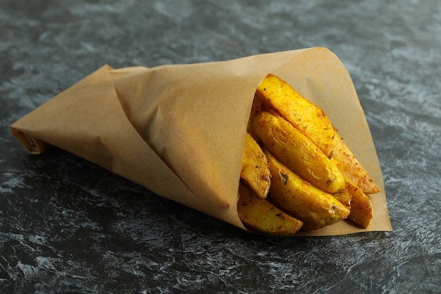 Baking paper with potato wedges on black smokey