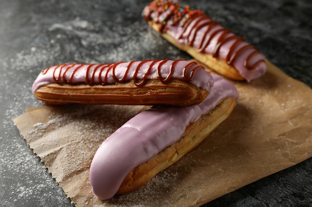 Baking paper with tasty eclairs on black smokey