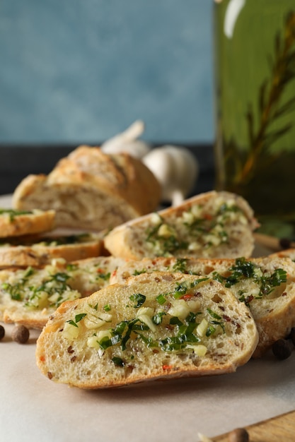 Baking paper with toasted garlic bread and oil on grey, close up