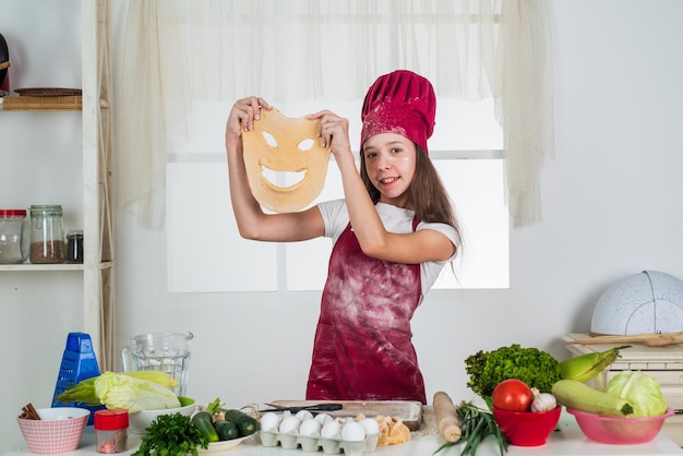 부엌에서 음식을 요리하는 베이킹 과정 아이 재미있는 반죽 요리와 요리로 경력 작은 도우미를 선택 행복한 어린 시절 행복한 아이는 모자와 앞치마를 입은 요리사 유니폼 요리사 소녀를 입는다