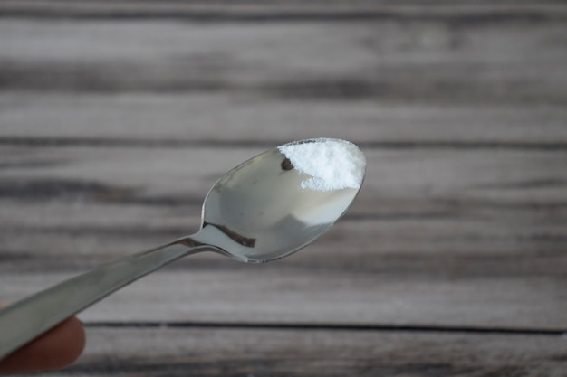 Baking soda on the tip of a small spoon on a wooden background