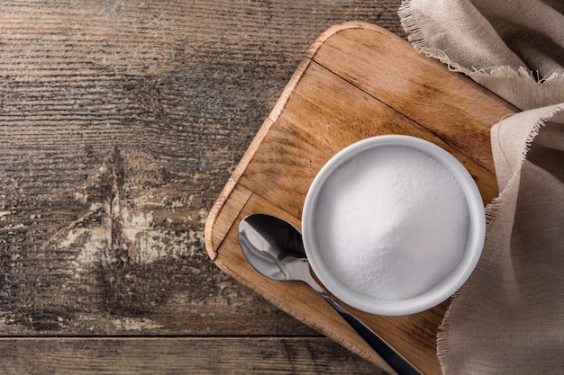 Baking soda in white bowl on wooden table top view copyspace