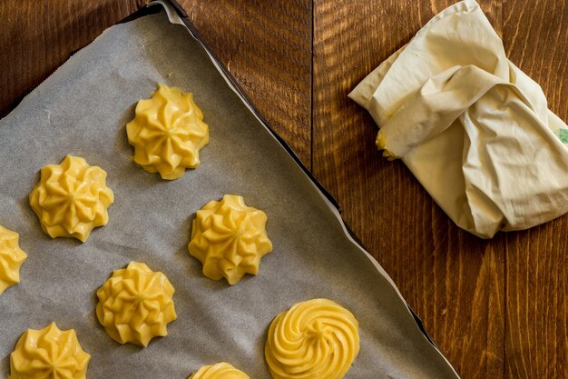 Foto un vassoio da cottura di pasticceria choux su uno sfondo di legno scuro pronto per essere cotto nel forno a legna domestico