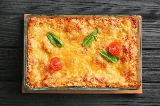 Baking tray with spinach lasagna on wooden table