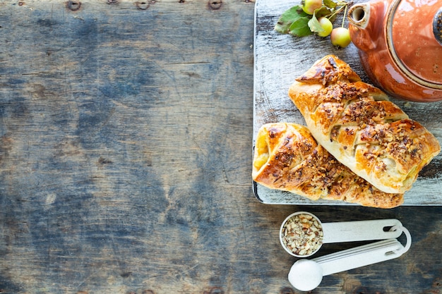 Baking with apple, Freshly baked apple and cinnamon rolls made from puff pastry on a white wooden table. Top view, rustic style, copy space.