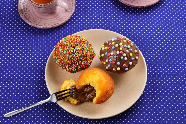 Photo baking with tea and chocolate on the table.  two cups of tea with cupcakes and chocolate with a multicolored powder on the table.