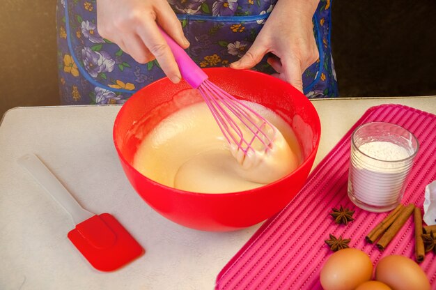 Bakingrediënten en gebruiksvoorwerpen voor het koken van biscuit. Proces koken biscuit. Vrouw die het deeg mengt