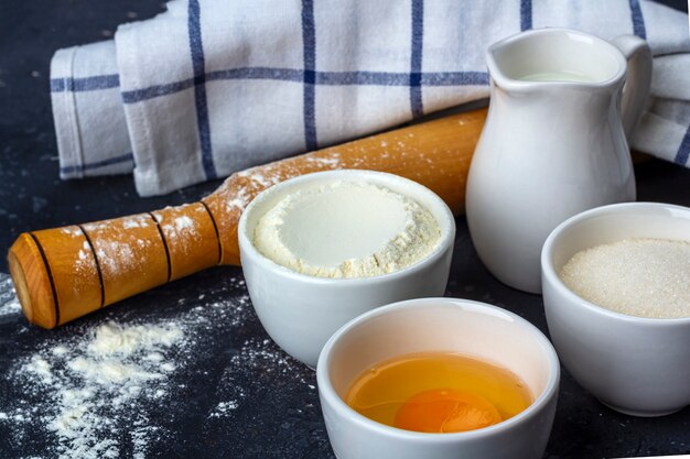 Bakken achtergrond. Ingrediënten en gebruiksvoorwerpen voor het koken van cake op donkere tafel. Voedsel concept.