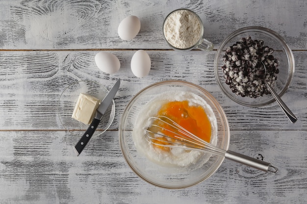 Bakken in rustieke keuken recept ingrediënten (eieren, meel, melk, boter) op witte houten tafel van bovenaf.