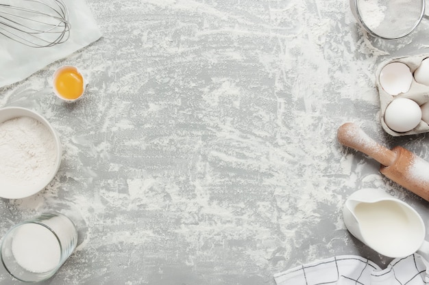 Foto bakken ingrediënten, keukengerei, op grijze betonnen ondergrond plat lag, kopieer ruimte. kerst- of nieuwjaarskoekjes, brood, gebak koken. bereid deeg van eieren, bloem, melk, olie, boter, suiker