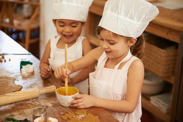 Bakken is zo leuk Twee kleine meisjes die plezier hebben tijdens het bakken in de keuken