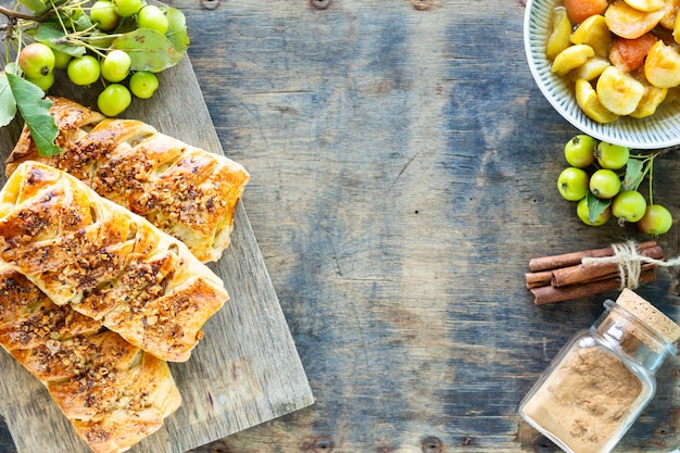 Bakken met appel, vers gebakken appel en kaneelbroodjes gemaakt van bladerdeeg op een witte houten tafel. bovenaanzicht, rustieke stijl, kopie ruimte.