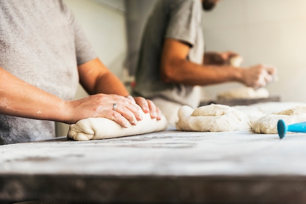 Bakker die brood klaarmaakt. sluit omhoog van handen die deeg kneden. bakkerij concept.