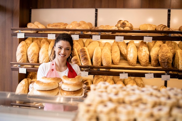 Bakkerij winkel interieur en werknemer in uniform staan bij de plank vol met vers gebakken gebak