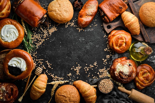 Bakkerijbroodjes met jam, kwark, maanzaad en sesam op een zwarte stenen achtergrond Bakken van rogge en bloem Bovenaanzicht Rustieke stijl