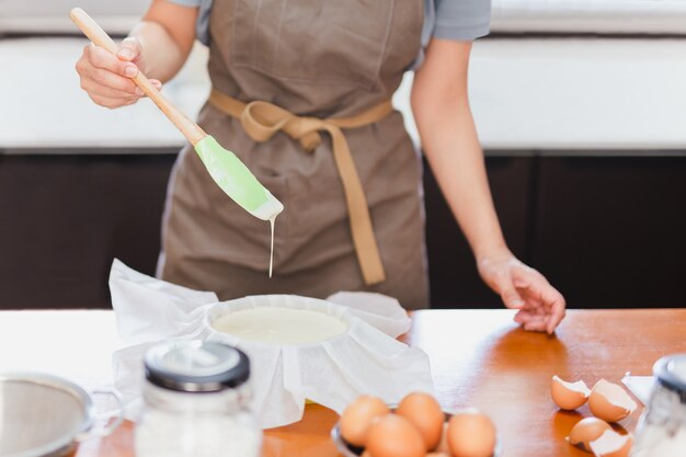 Bakkersvrouw bereidt cakemixdeeg in vorm voor bakvorm