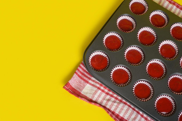 Bakkie met een mengsel van rode fluweel cupcake ingrediënten klaar om te bakken Gele achtergrond
