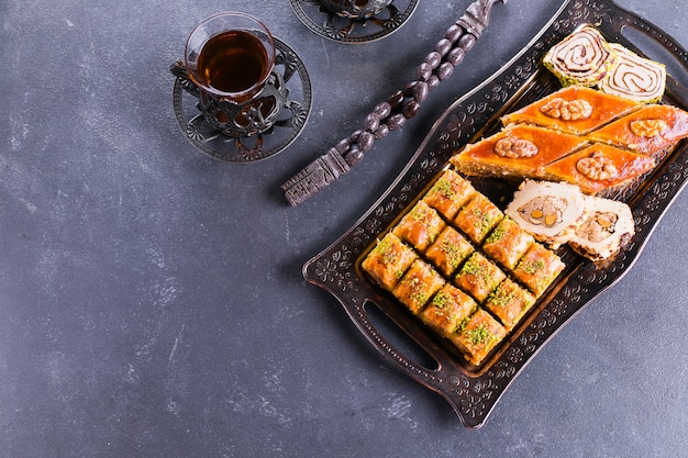 Baklava. Ramadan Dessert. Assortiment van Arabische dessert met noten en honing, kopjes thee op een betonnen tafel. Bovenaanzicht, kopieer ruimte