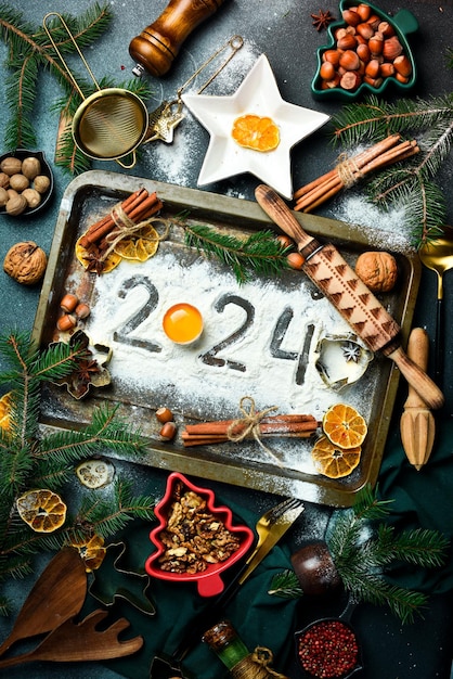 Foto bakmeel en het nummer 2024 op het bord top view nieuwjaars eten achtergrond kerstversieringen geschenken sparbomen top view flat lay