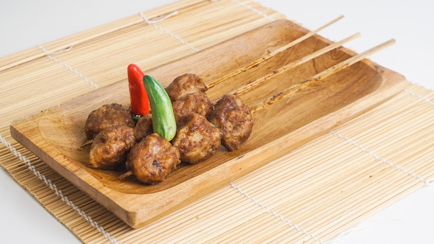 Bakso bakar is Indonesian grilled meatballs served on wooden plate