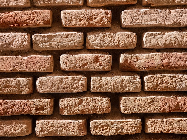 Foto bakstenen muur gemaakt met stenen en grote openingen tussen hun voegen als gevolg van erosie en het verstrijken van de tijd