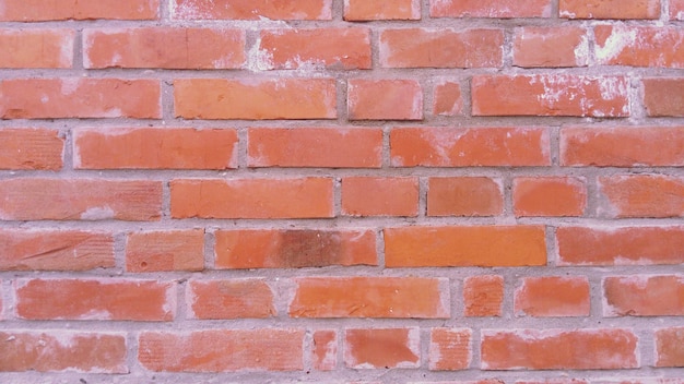 Bakstenen muur gemaakt van felrode bakstenen Licht versleten oppervlak Netjes metselwerkcement tussen de rijen Grunge achtergrond De buitenkant van het gebouw Het interieur van de kamer Gevelbekleding