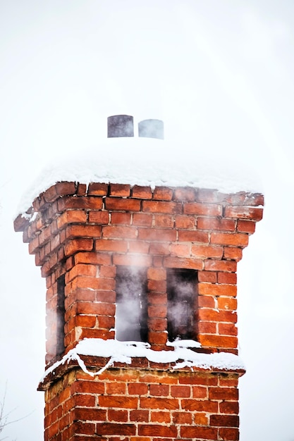 Foto bakstenen schoorsteen en rook ervan in de winter close-up