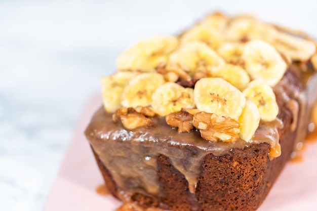 Bakt vers een brood van bananennotenbrood besprenkeld met zelfgemaakte karamel op een roze snijplank.