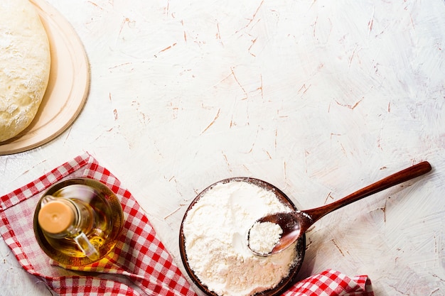 Bal deeg op de keukentafel, olijfolie in een fles met kopieerruimte. Pizzadeeg kneden. Rustiek brood, zelfgemaakt. Hoge kwaliteit foto