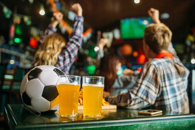 Foto bal en bier op tafel in de sportbar, voetbalfans