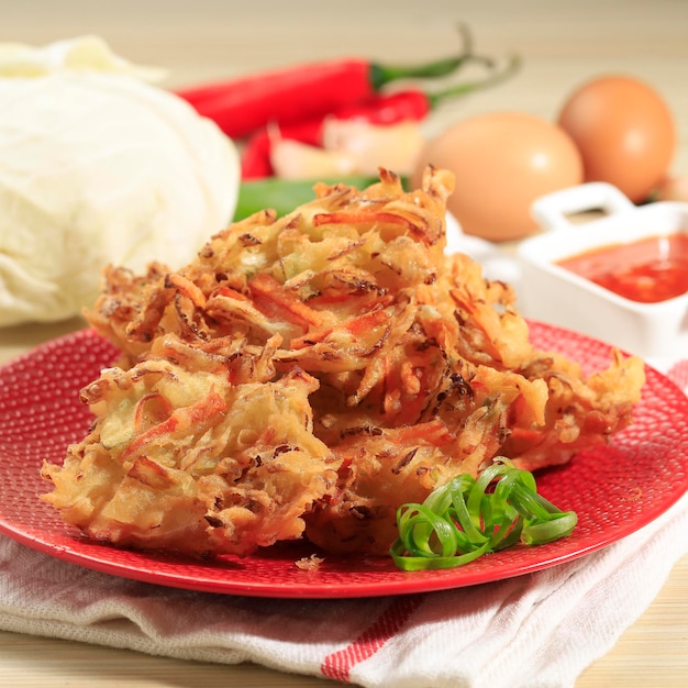 Bala-bala is Vegetable Fritters, Popular Street Food in Indonesia. Easy to Make at Home for Break Fasting. Served on the Red Plate