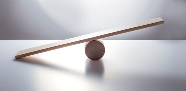 Фото Концепция баланса, доска на деревянном цилиндре, как баланс, изолированные на белой поверхности