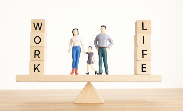 Концепция баланса между жизнью и работой Семейные фигурки и деревянные блоки со словом на качелях