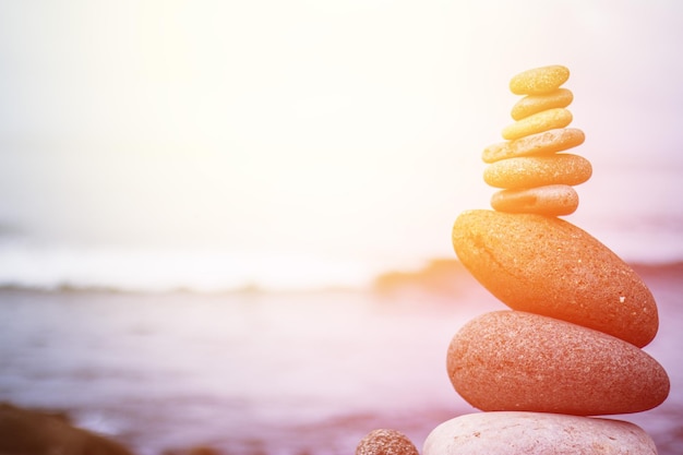 Balance relaxation and wellness Stone cairn outside ocean in the blurry background Sunshine