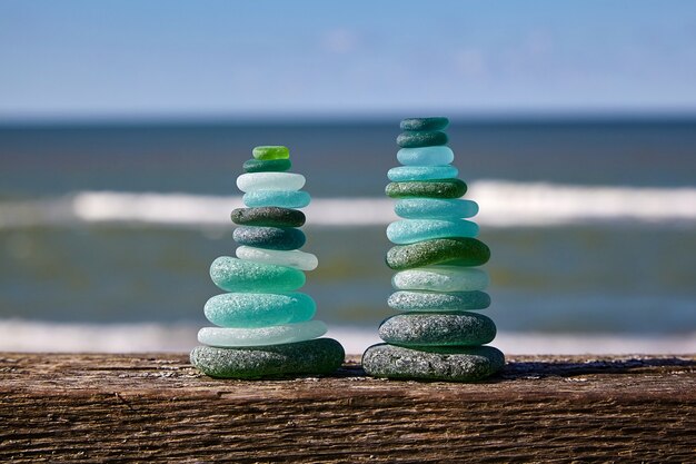 Balance of stones. Glass stones on a wooden table against the sea. Two towers