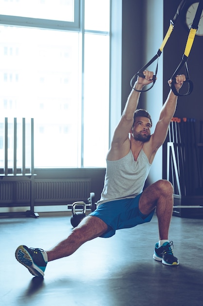 Balance and strength. Full-length of young man in sportswear exercising at gym