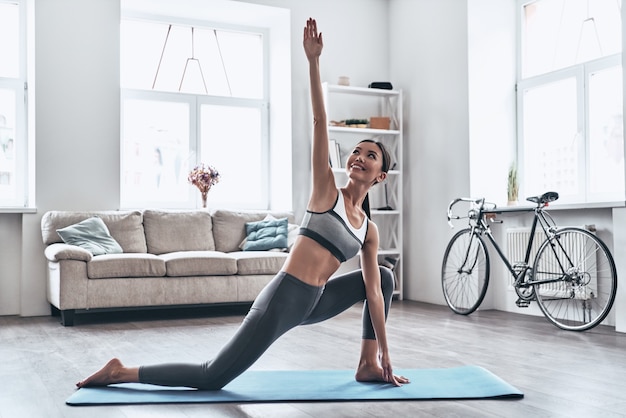 Balance your life. Beautiful young Asian woman in sports clothing doing yoga while relaxing at home