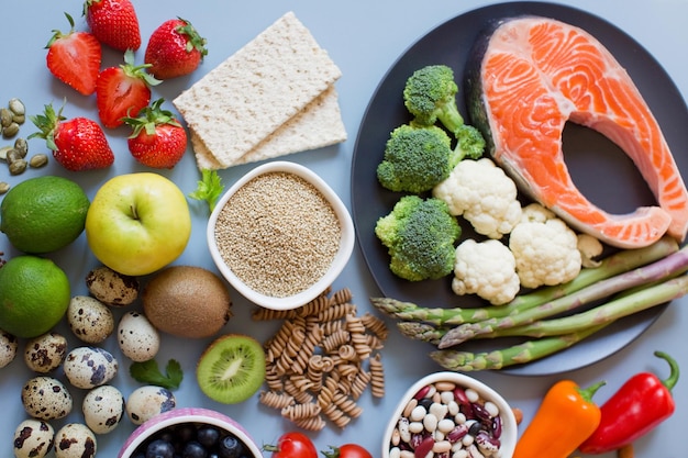 Balanced diet food background. Fresh vegatables, fruits, cereals, seeds and nuts on a blue background.