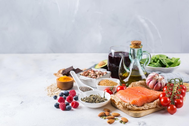 Balanced diet food concept Assortment of healthy food low cholesterol spinach avocado red wine green tea salmon tomato berries flax chia seeds turmeric garlic nuts olive oil Copy space background