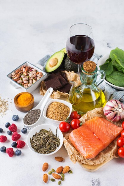 Balanced diet food concept Assortment of healthy food low cholesterol spinach avocado red wine green tea salmon tomato berries flax chia seeds turmeric garlic nuts olive oil