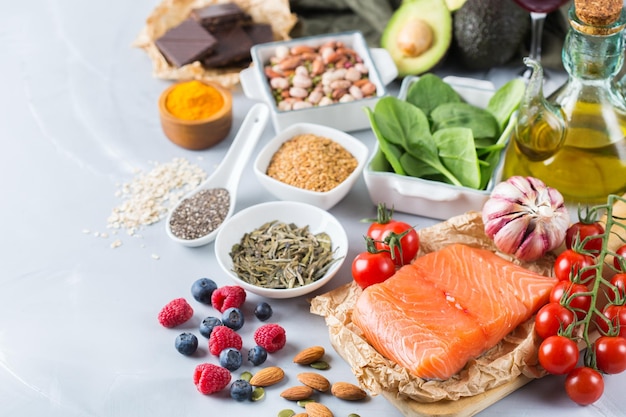 Balanced diet food concept Assortment of healthy food low cholesterol spinach avocado red wine green tea salmon tomato berries flax chia seeds turmeric garlic nuts olive oil