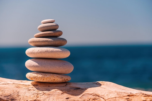 Balanced pebble pyramid on the beach on a sunny day abstract sea bokeh on the background selective