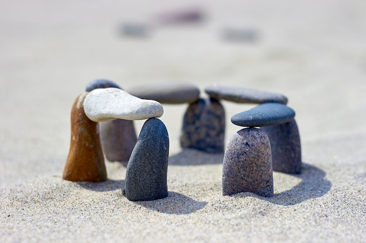 Photo balanced pebbles on the sandy coast. stones are stacked on the beach. little stonehenge
