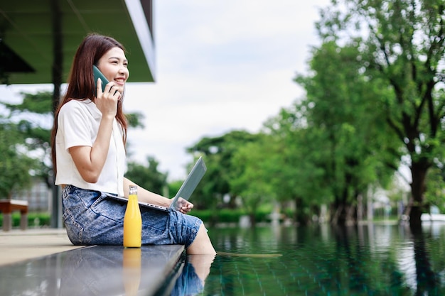 Balancing Relaxation and Connectivity Woman on Vacation Checks Social Media by the Pool with Smartphone