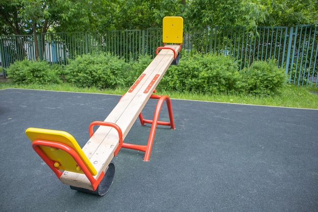 Foto altalena in equilibrio a forma di tavola di legno su un'area giochi per bambini vuota con parco giochi all'aperto